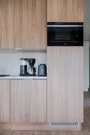 A kitchen with wooden cabinets, a built-in microwave, a coffee maker, and a toaster. - Äkäsentie 1 A 305 by Holiday in Lapland (Äkäslompolo)