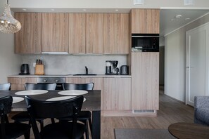 A modern kitchen with wooden cabinets, a dining area with a table and chairs, and a built-in microwave. - Äkäsentie 1 A 305 by Holiday in Lapland (Äkäslompolo)