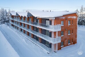 Ein mehrstöckiges Gebäude mit verschneitem Dach und einem Balkon im Erdgeschoss.