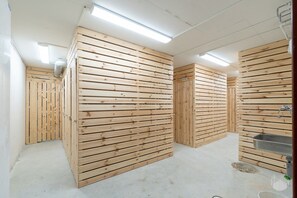 Une pièce aux murs recouverts de panneaux de bois, une porte visible portant le numéro 210 et un évier en métal.