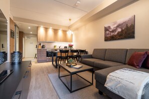 Een moderne woonkamer met een bank, een salontafel, en een eethoek met stoelen en een tafel.