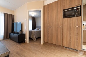 Een slaapkamer met een bed, een televisie, een kledingkast en een magnetron.