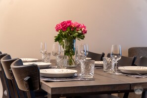 Een eettafel gedekt met borden, glazen en een bloevas.