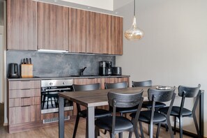 Eine moderne Küche mit Holzschränken, einem eingebauten Backofen und einem Essbereich mit Tisch und Stühlen.