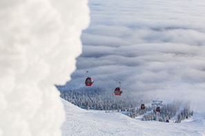 A ski lift with cabins suspended by cables, surrounded by a snowy landscape and trees. - Holiday in Lapland - Sivulantie 4 105 (Äkäslompolo)