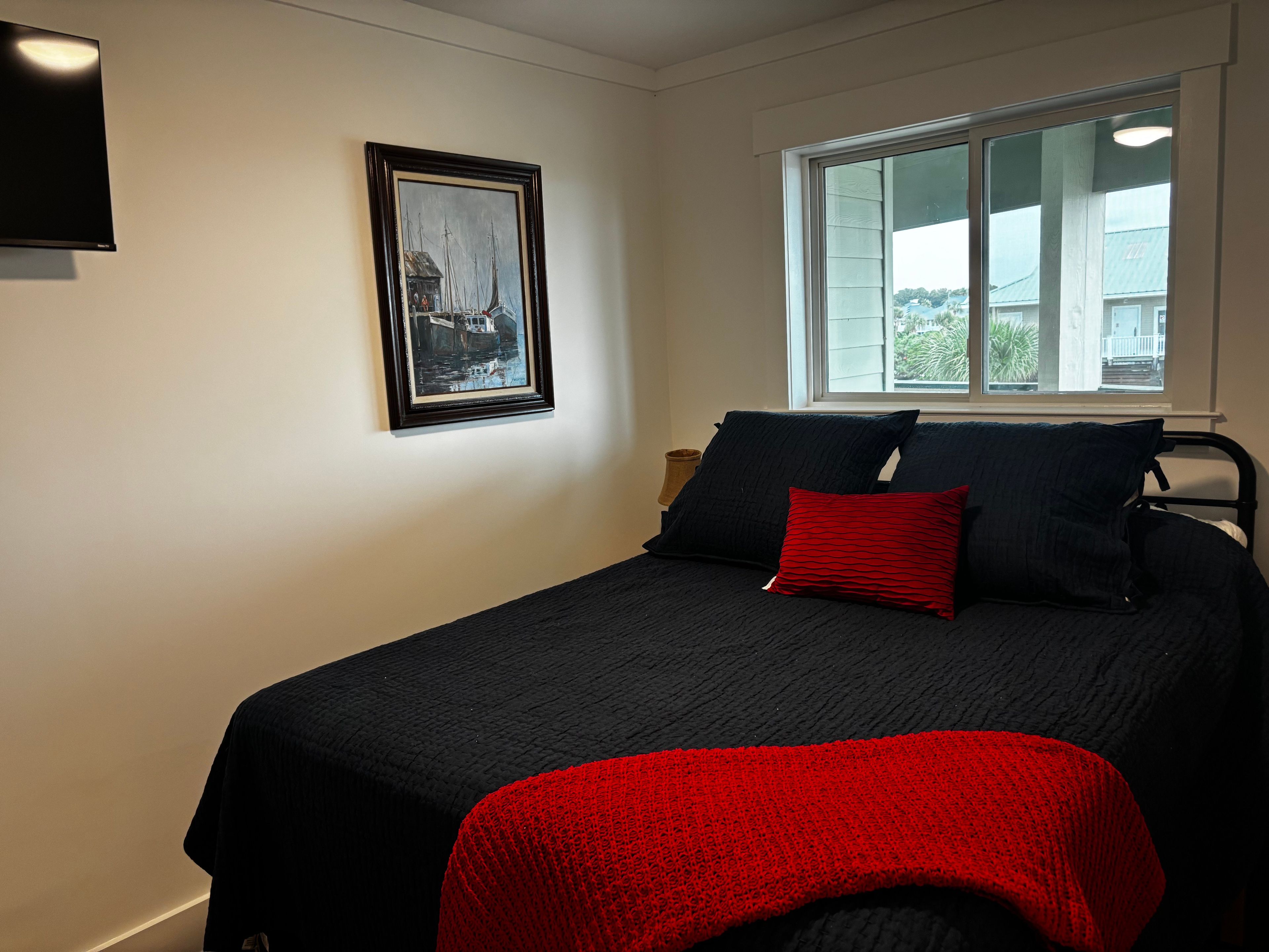 Une chambre à coucher avec un lit, une fenêtre et un tableau encadré au mur.