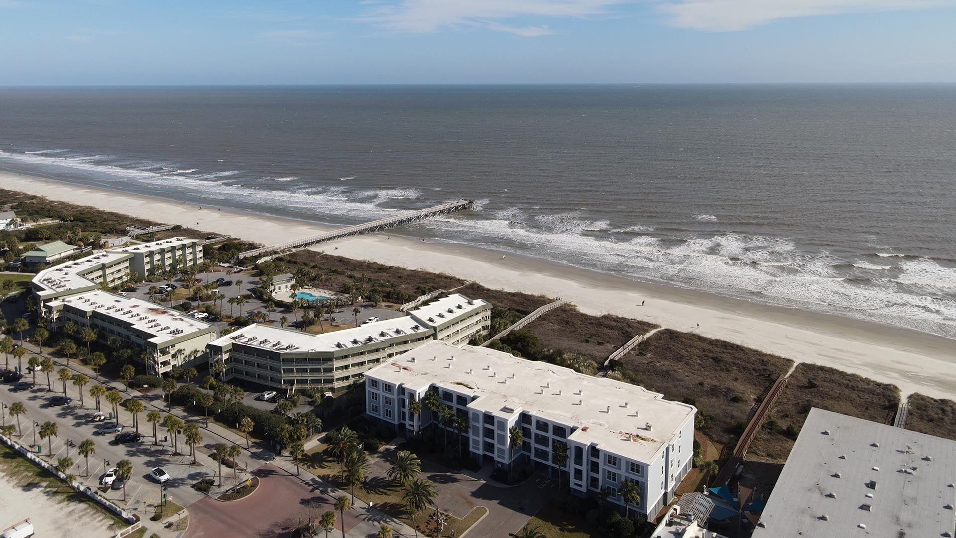 A coastal hotel with multiple buildings, a beach, and a pier.