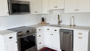Una cocina con armarios blancos, electrodomésticos de acero inoxidable y piso de madera.