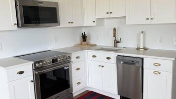 Una cocina con armarios blancos, electrodomésticos de acero inoxidable y piso de madera.