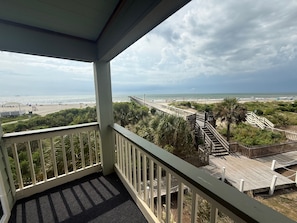 Uma varanda com vista para a praia e um calçadão.
