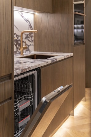 A modern kitchen with a built-in dishwasher, wooden cabinets, and a marble countertop. - Acropolis Luxury Penthouse with Private Jacuzzi, Apartment (Athens)