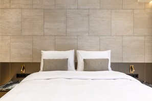 A hotel room with a large bed, two bedside tables, and a headboard with a textured design. - Acropolis Luxury Penthouse with Private Jacuzzi, Apartment (Athens)