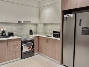 A modern kitchen with a stainless steel refrigerator, a built-in oven, and a microwave.
