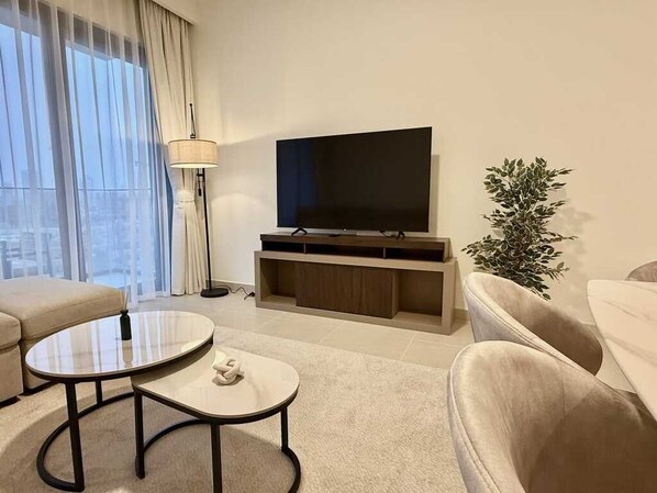 A modern living room with a flat-screen TV, a sofa, a coffee table, and a floor lamp.