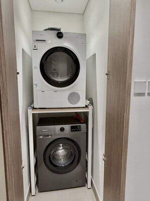 A compact laundry room with two stacked washing machines, one above the other, and a dryer below. - 2BR at Seagate Marina  Yacht Views, Sleeps 6, Pool and Gym (Dubai)