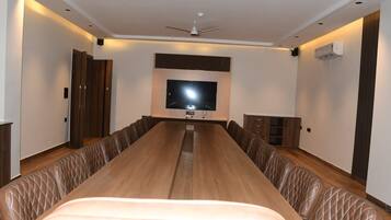 A conference room with a long table, leather chairs, a flat-screen TV, ceiling fans, and built-in cabinets.
