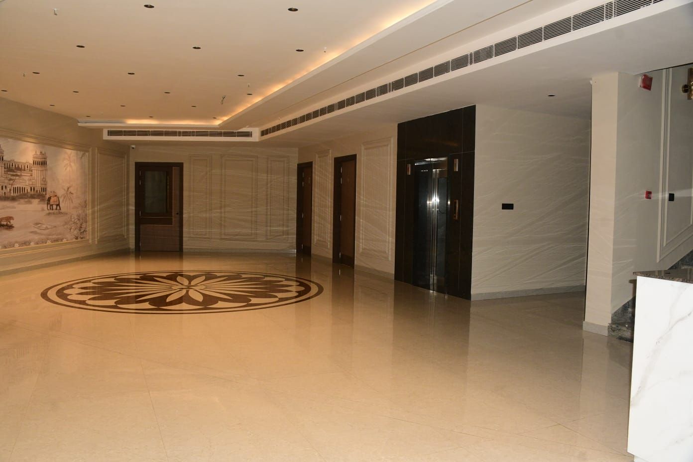 A spacious lobby with a polished floor, a large decorative emblem, and a mural on the wall.