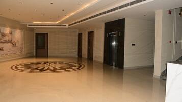 A spacious lobby with a polished floor, a large decorative emblem, and a mural on the wall.