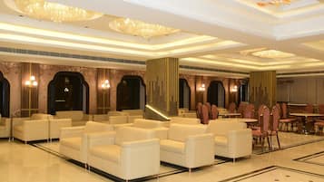 Un amplio vestíbulo de hotel con asientos cómodos, candelabros y un suelo pulido.