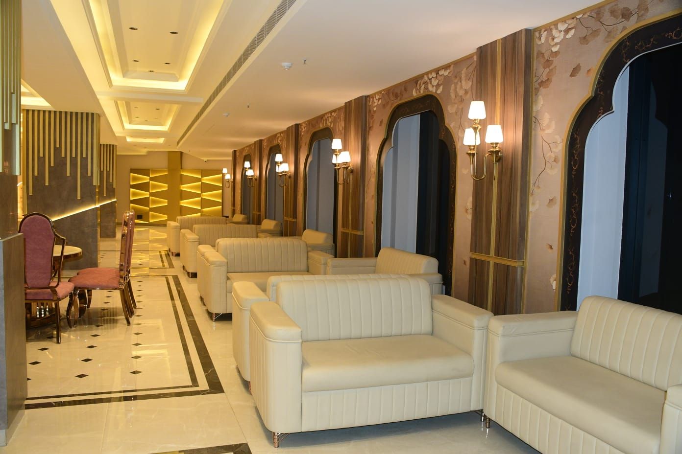Un vestíbulo de hotel con distribuciones de asientos, una zona de recepción y paneles decorativos en las paredes.