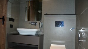 Un baño moderno con lavabo, espejo y inodoro blancos.
