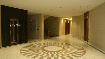 A hotel corridor with a central circular floor design, elevators, and doors.