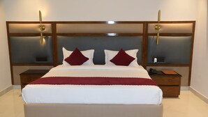 Una cama grande con cabecera de madera, dos mesitas de noche y una manta roja.