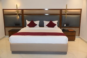 A large bed with a wooden headboard, two bedside tables, and a red throw blanket. - INDUS VALLEY (Bulandshahr)