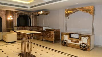 Un vestíbulo de hotel con una zona de estar, una mesa y un carrito decorativo.