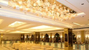 Un hall de hotel con zona de estar, una recepción y un techo decorativo.