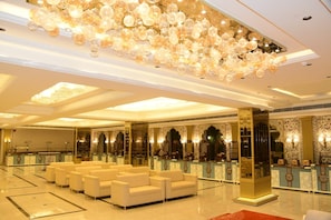 A hotel lobby with a seating area, a reception desk, and a decorative ceiling. - INDUS VALLEY (Bulandshahr)