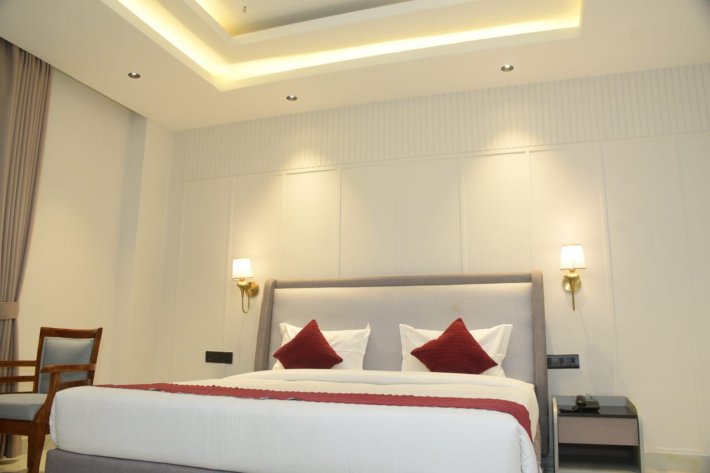 A hotel room with a bed, two nightstands, a chair, and a ceiling light fixture.