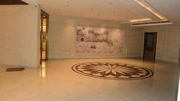 Eine geräumige Lobby mit einer großen Wandmalerei eines historischen Gebäudes, einem polierten Boden und einem modernen Deckenstil.