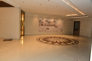 A spacious lobby with a large mural of a historical building, a polished floor, and a modern ceiling design.