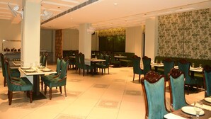 Un restaurante con varias mesas y sillas, una pared con diseño y un techo con iluminación empotrada.