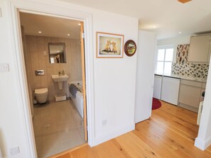 A modern kitchen with white cabinets, a tiled backsplash, and a wooden floor. - Wayside (Moreton-in-Marsh)