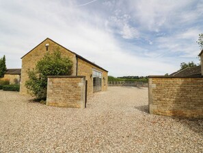 A stone building with a gravel driveway and a wooden fence. - Wayside (Moreton-in-Marsh)