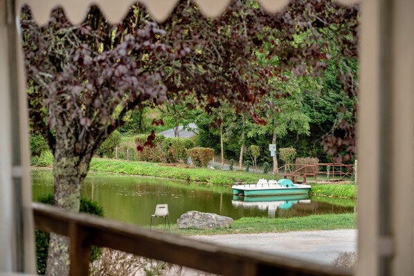 A tranquil park with a pond, a boat, and a wooden bridge.