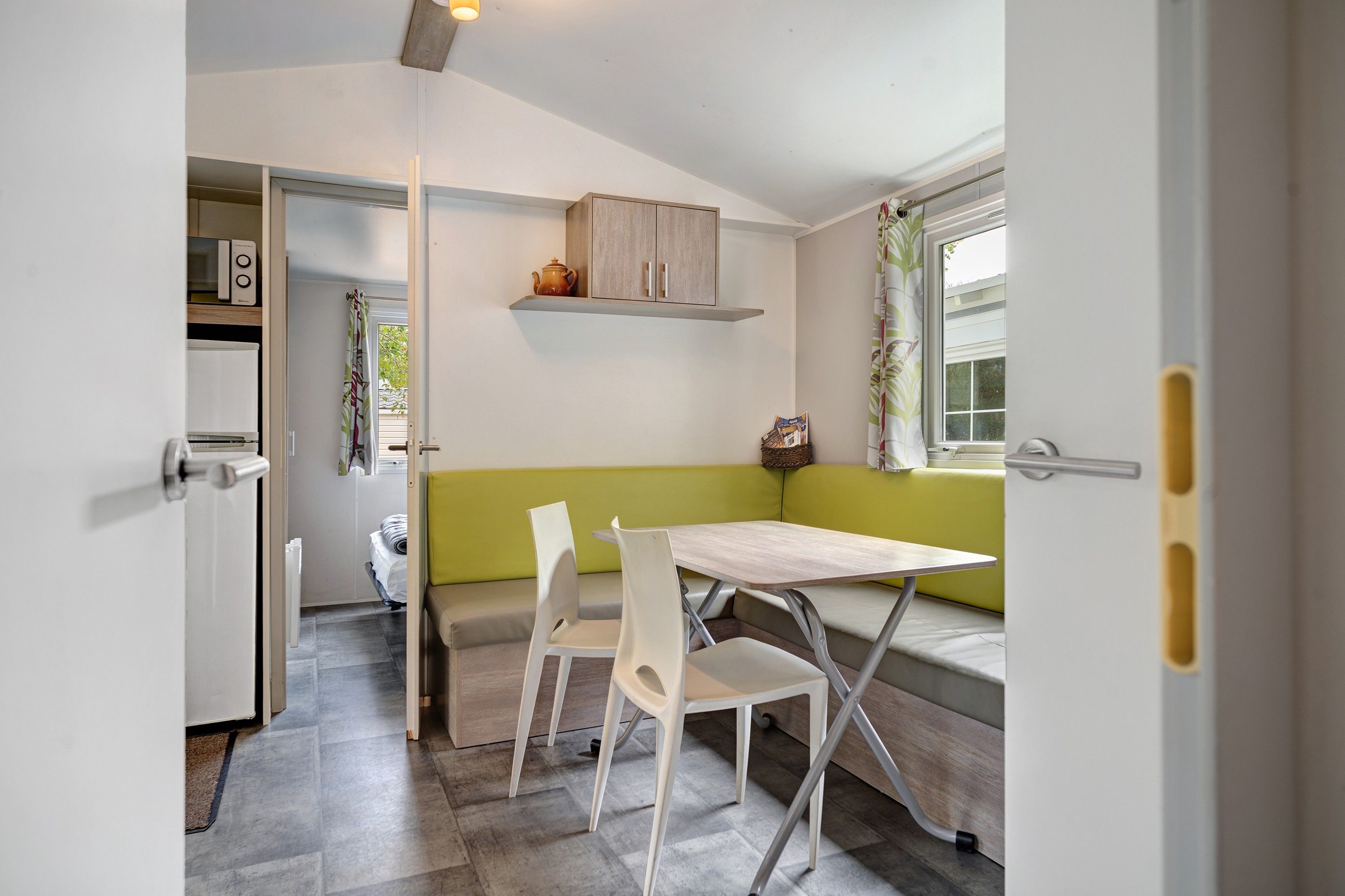 Une cuisine compacte avec un coin repas comprenant une table et des chaises, un banc et une fenêtre avec des rideaux.