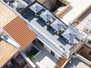 Eine Dachterrasse mit mehreren Sonnenschirmen, einem Wassertank und einem Ziegeldach.