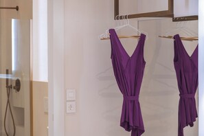 A room with a white wall, a wooden hanger rack with purple garments, and a white electrical outlet. - Verano suites- Economy interior suite, Luxury suites in the center of Rethymno (Rethymno)