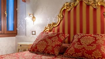 A bed with ornate headboard and red patterned bedding.
