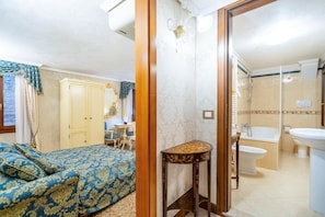A bedroom with a bed, a desk, and a bathroom with a bathtub and sink. - Casa Guggenheim (Venezia)