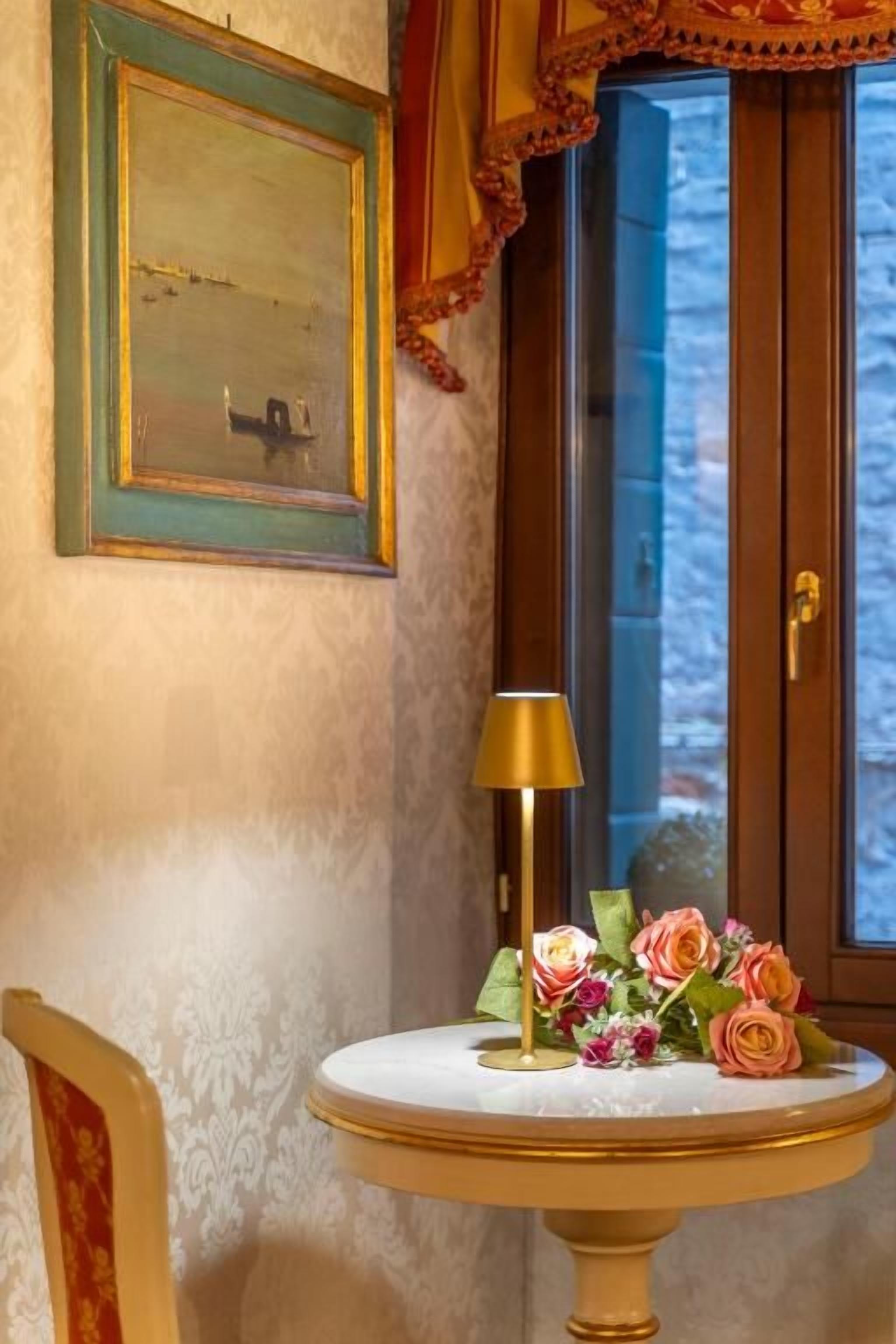 A room with a round table, a lamp, and a floral arrangement.