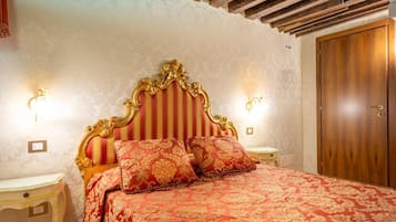 Un dormitori amb un llit gran, un panell de capçal amb trets decoratius, dues taules de nit i un armari de fusta.