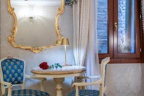 A room with a round table, two chairs, a mirror, a lamp, and a door with a window. - Casa Guggenheim (Venice)