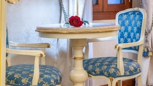 Ein Zimmer mit einem runden Tisch, zwei Stühlen, einem Spiegel und einem Fenster mit Vorhängen.