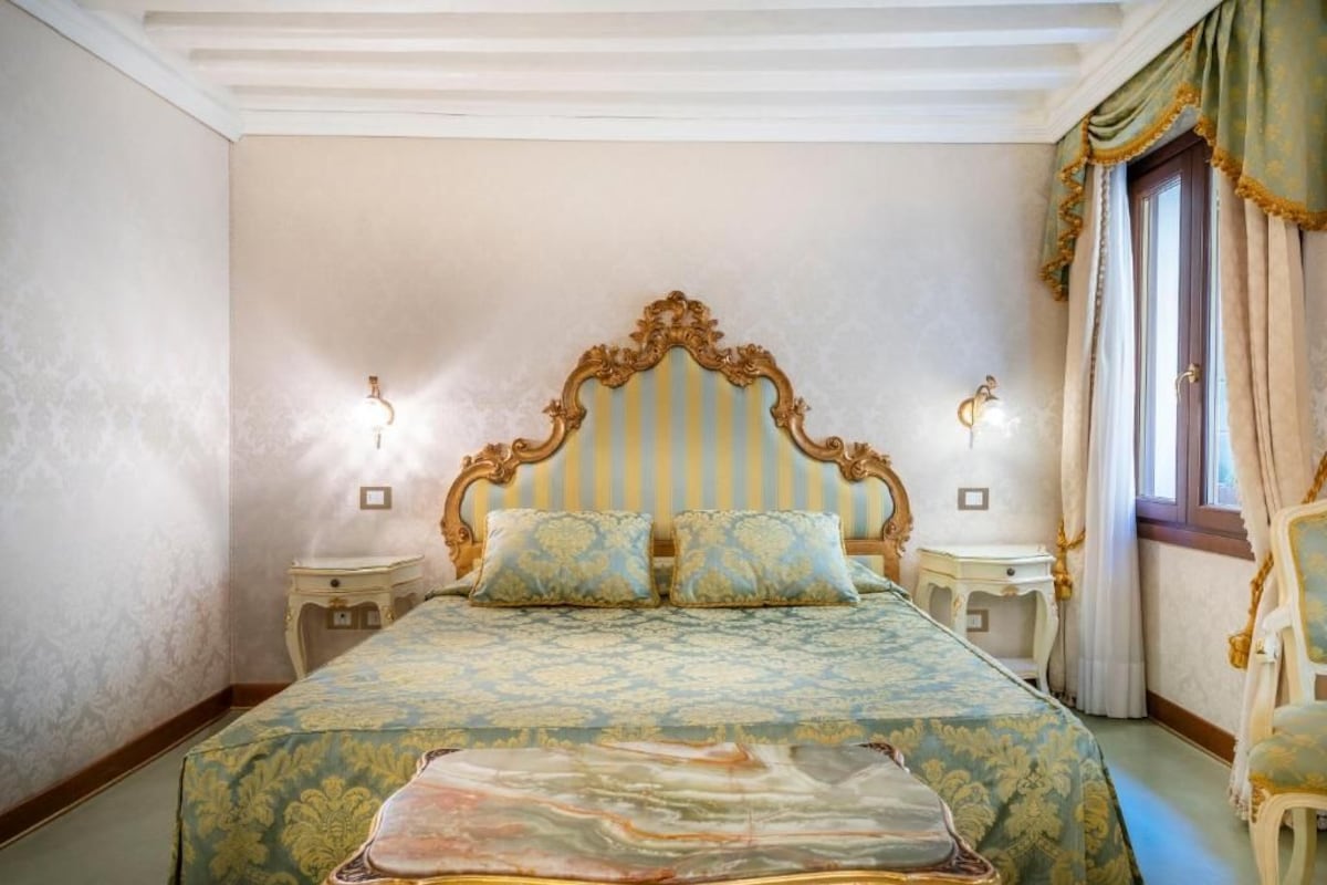 A bedroom with a large bed, two bedside tables, and a window with curtains.