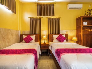 Habitación de hotel con dos camas, una mesita de noche con lámpara, un armario y un equipo de aire acondicionado en la pared.