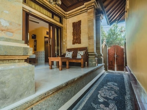 A hallway with a wooden bench, a tiled floor, and a patterned rug.